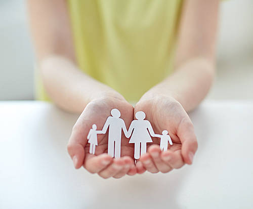 people, charity and care concept-close up of child hands holding paper family cutout at home