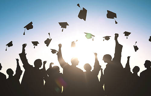 education, graduation and people concept-silhouettes of many happy students in gowns throwing mortarboards in air