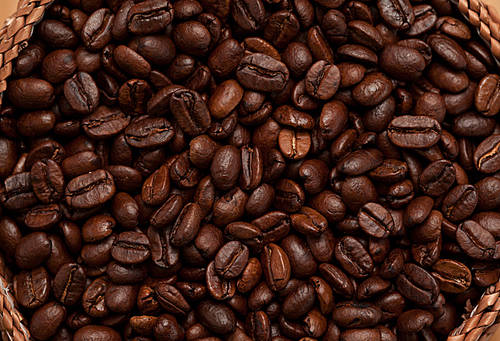 Close up of a basket full of dark coffee beans