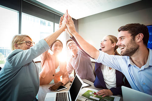 Business people giving high five at desk in the office