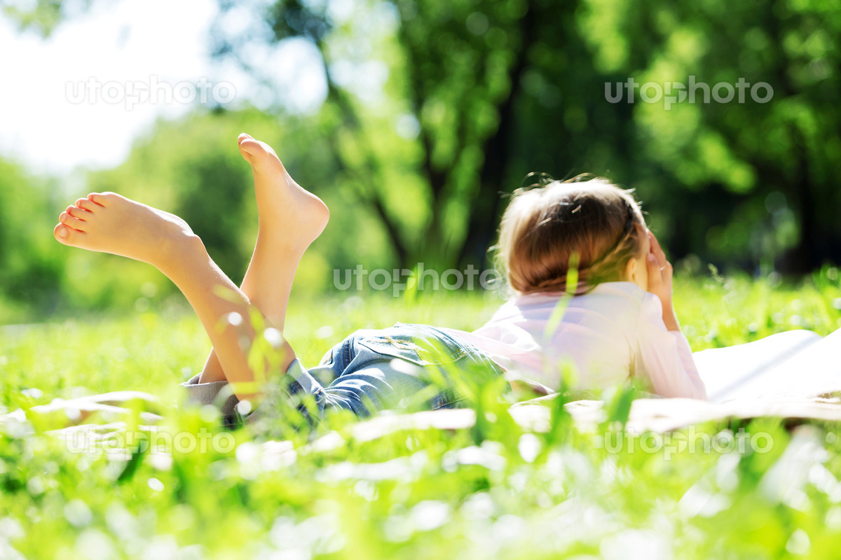Child lying on blanket having picnic in summer park