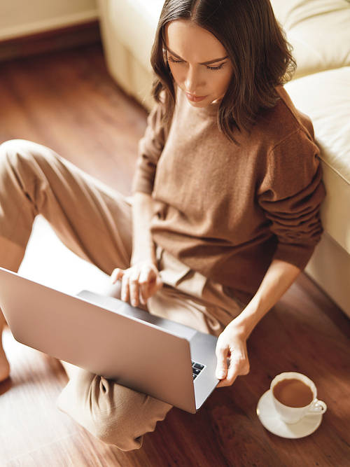 Lifestyle portrait of beautiful lady working at notebook sitting down on floor at home. Woman concept for alternative office freelance. Stay home