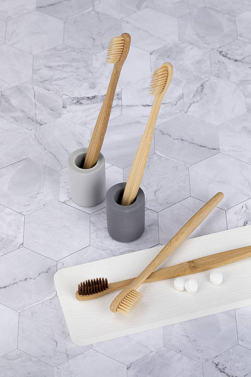 Zero waste - bamboo toothbrush and solid toothpaste in a gypsum toothbrush stand on marble background
