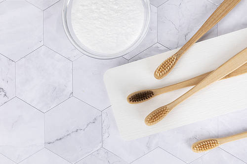 Zero waste-marble background, bamboo toothbrush and baking soda on a plaster tray