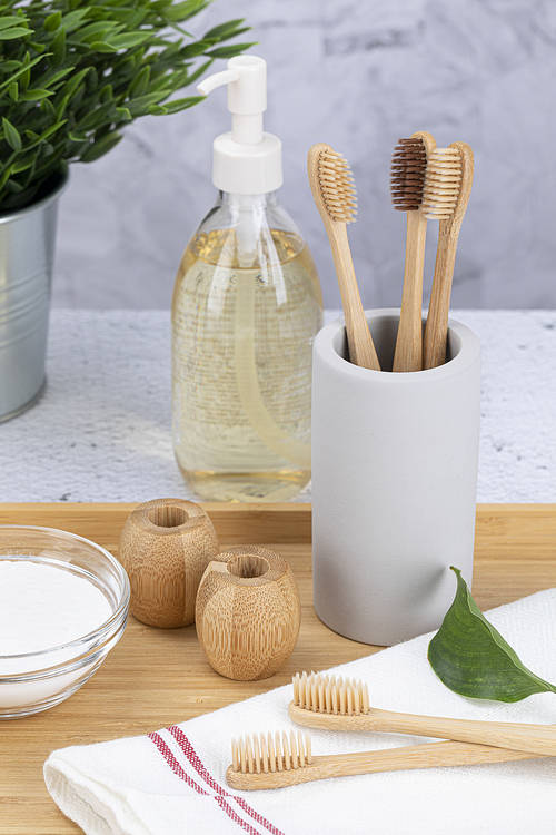 Zero Waste - Baking soda, bamboo toothbrush, bamboo toothbrush holder and body oil, flowerpot on a wooden tray