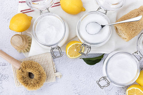 Zero Waste - Glass jar and wooden spoon with bamboo cleaning brushes, lemon, natural loofahs and citric acid powder, baking soda and percarbonate powder on linen cloth, top frame