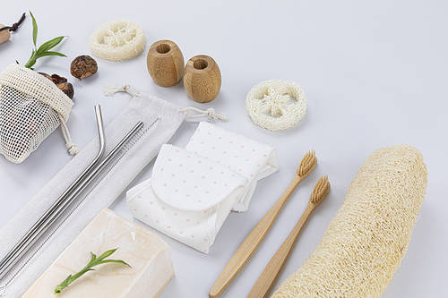 Zero Waste-Natural loofah and cleaning brushes in basket, bamboo toothbrush and bamboo toothbrush holder, stainless straws and cleaning brush, glass bowl with baking soda and softnut and natural soap and natural cotton sanitary napkin, close-up