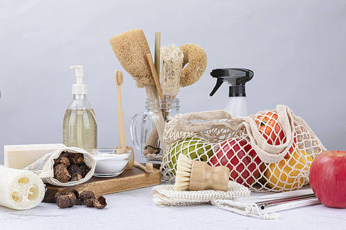 Zero Waste-Soapnut and natural soap on a wooden chopping board, glass bowls and softeners with baking soda, bamboo toothbrush and toothbrush holder, net net with fruit and natural loofah and cleaning brushes, bamboo straws and stainless straws, and for cleaning sprayer