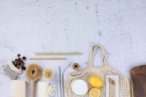 Zero-waist-a pouch with a soft nut and natural soap, bamboo straws and stainless straws, bamboo toothbrush and toothbrush holder, net bag and lemon, a glass bowl with baking soda, natural loofah and cleaning brushes, wooden cutting board, top frame