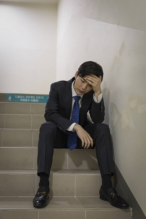 A young new employee's day-A tough young new employee sitting on the stairs and resting