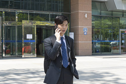 A day of a young new employee - A young new employee is calling on a smart phone in front of the company