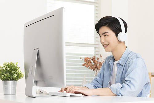 Wise student life - young man with headset typing while looking at computer monitor