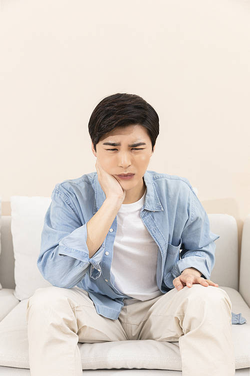 Wise job hunting life - sick young man with toothache sitting on sofa