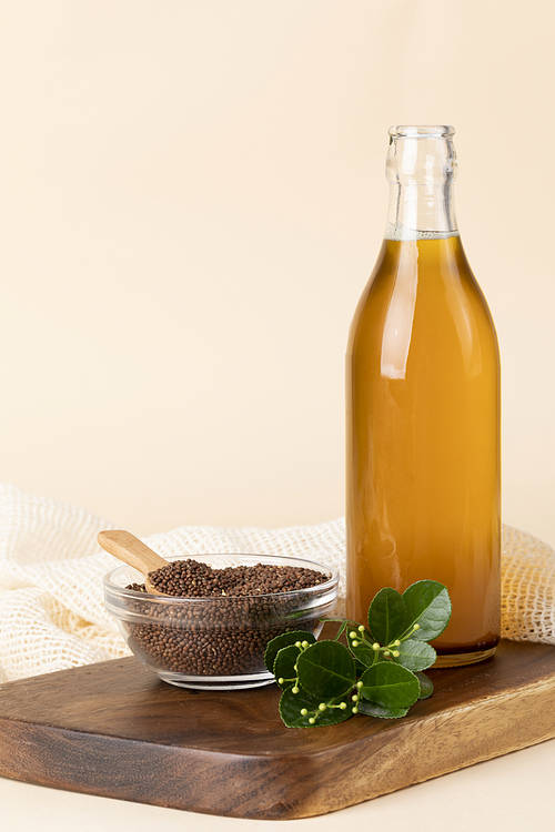 Sesame seeds - a bottle of perilla oil placed on a wooden cutting board, a glass bowl with perilla seeds, and a wooden spoon