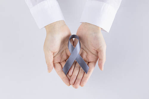 Ribbon - An image of two hands wearing a white shirt holding a gray ribbon