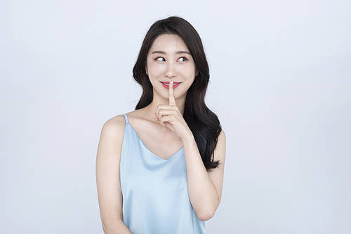Makeup - A woman who smiles while making a hand gesture to say “Shh”