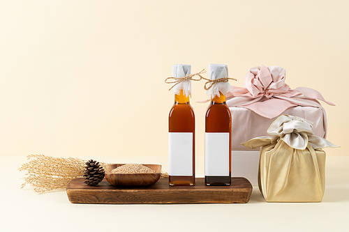 Holiday gift set_ A front image of a box wrapped in a pine cone cloth and a set of reed sesame oil in a bowl