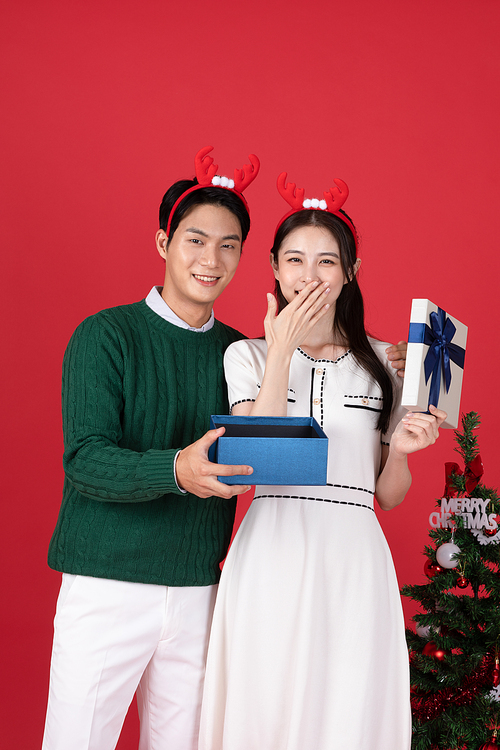 Rudolph headband Christmas shopping event concept photo of a couple rejoicing after opening a gift box