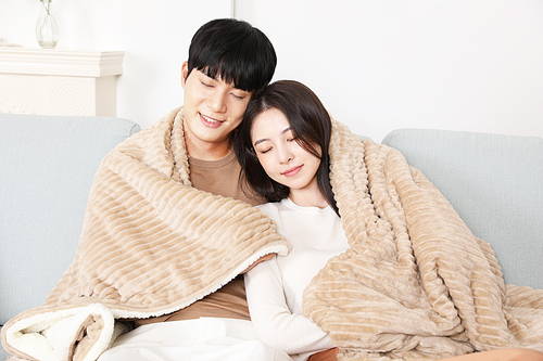 Lovers sitting on the sofa and resting under a blanket