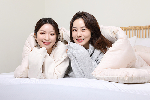 Winter indoor daily life_Picture of two women covering a duvet in bed