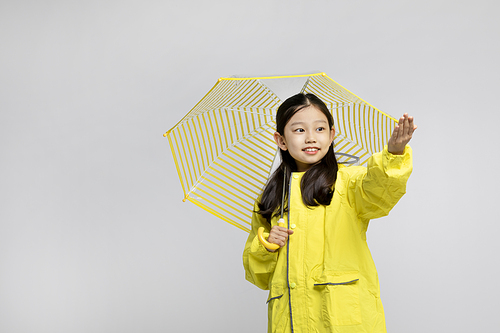 Photo image of a child wearing a raincoat and using an umbrella