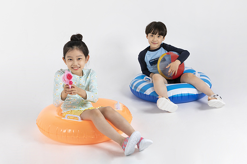 Photo image of a child sitting on a tube and holding a water gun