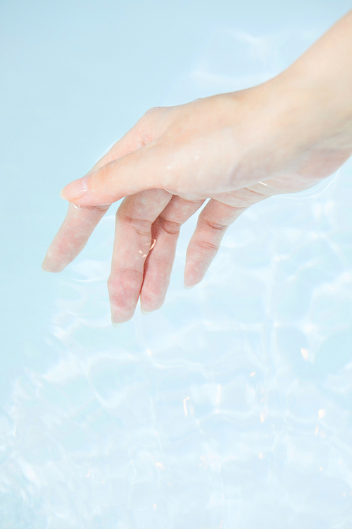 Photo image of female hands mixing Dead Sea salt in bathtub