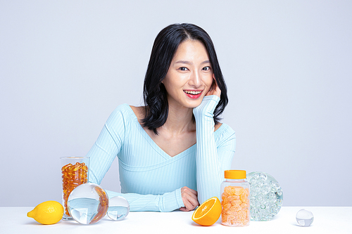 Healthy meal_Photo image of a woman sitting in front of a pill, lemon, tangerine, and orange