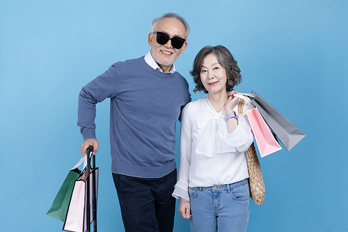 Travel after retirement_Photo image of a senior holding a suitcase and shopping bags