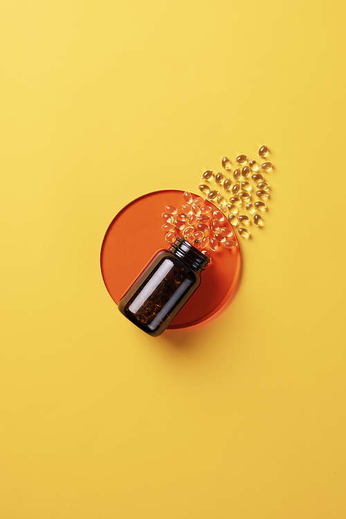 Yellow capsule medicine pouring out of a medicine bottle