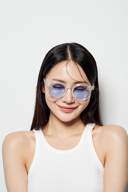 Asian woman wearing transparent sunglasses, closing her eyes and smiling