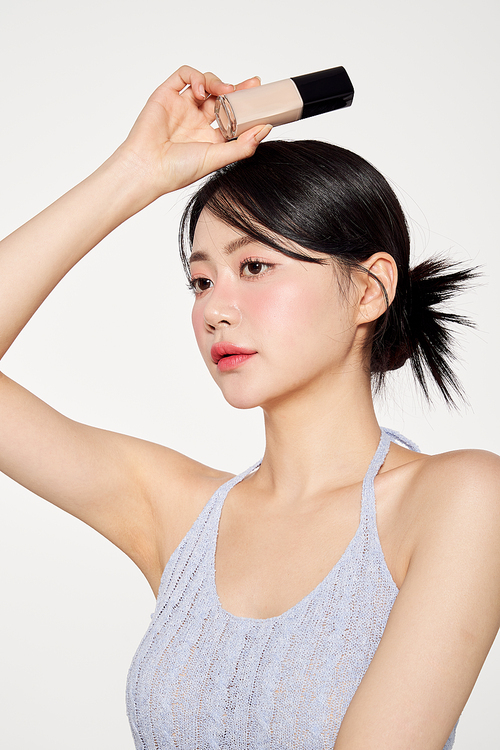 Asian woman posing while holding foundation over her head
