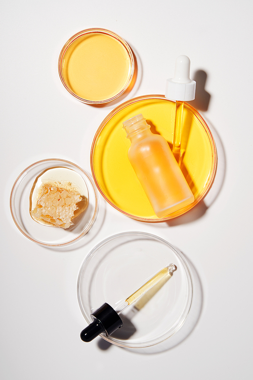Dropper and natural honeycomb with yellow ampoule placed on a petri dish