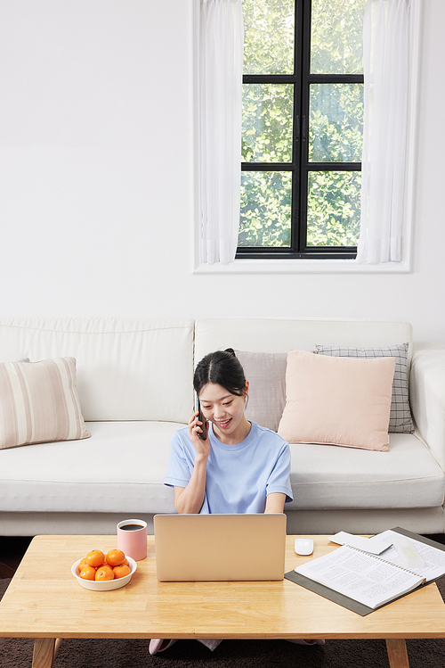 Woman talking on cell phone and looking at laptop