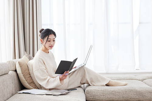 A woman leaning on the sofa and opening a notebook