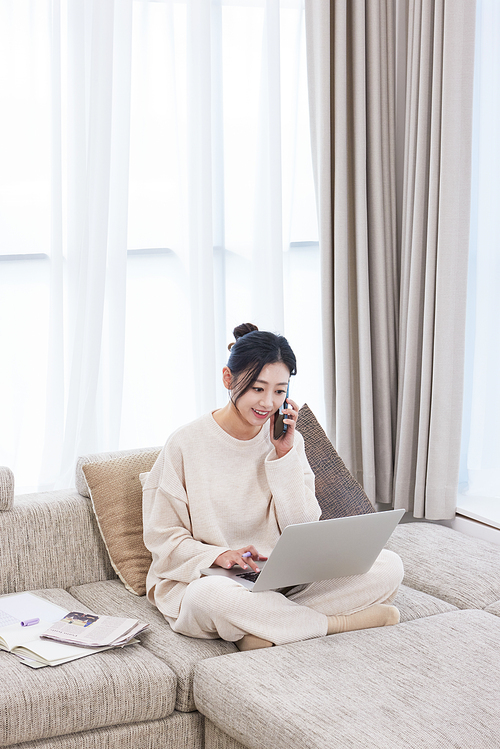 A woman sitting cross-legged on the sofa and working on her cell phone