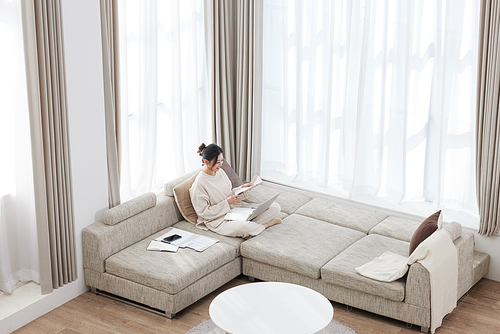 A woman sitting cross-legged on the sofa and working on a laptop