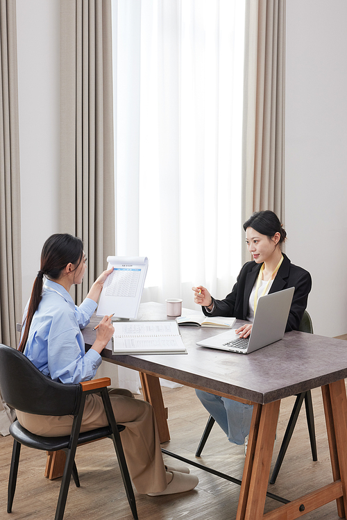 Two Asian women holding documents and having a meeting