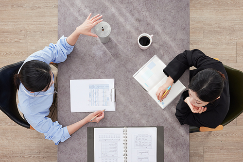 Two business women meeting at a desk viewed from above