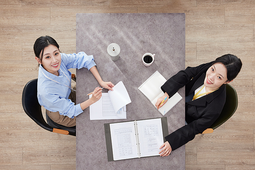 Two business women sitting at desk and looking up