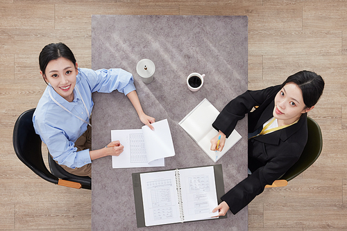 Two business women sitting at desk and looking up