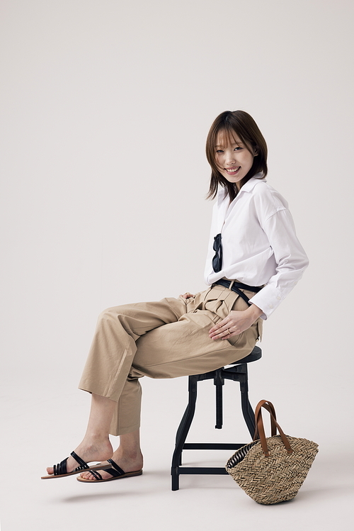Korean woman wearing trendy outfit sitting on chair with legs crossed