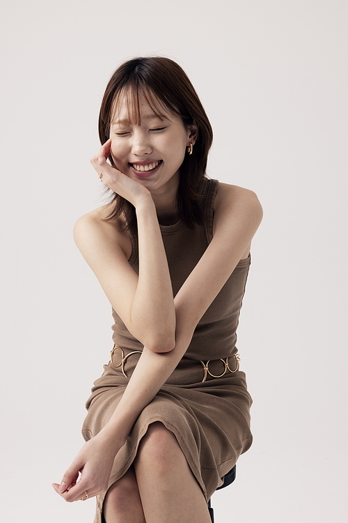 Korean woman posing while sitting on a chair wearing a beige knit dress