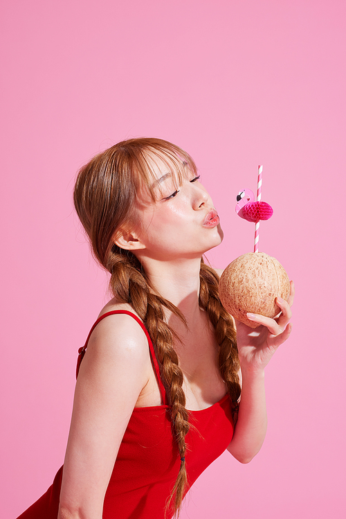 A Korean woman in her 20s wearing a monokini look and holding a coconut drink.