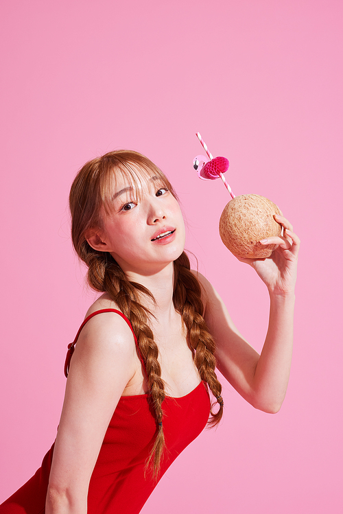 A Korean woman in her 20s wearing a monokini look and holding a coconut drink.