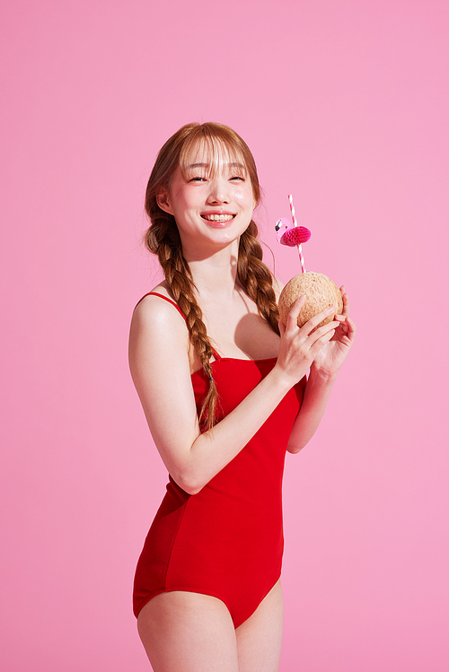 A Korean woman in her 20s wearing a monokini look and holding a coconut drink.