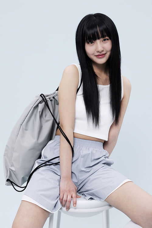 A Korean woman in her 20s wearing a block core look and posing while sitting on a chair.