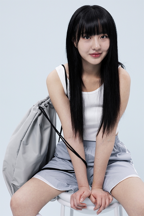 A Korean woman in her 20s wearing a block core look and posing while sitting on a chair.