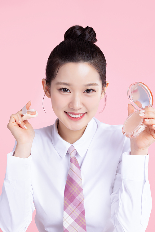 A teenage woman wearing a school uniform and holding cosmetics in a cute pose