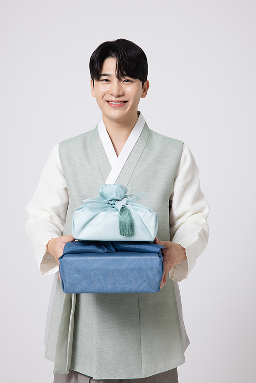 Portrait of a young man wearing hanbok and holding a luxurious holiday gift